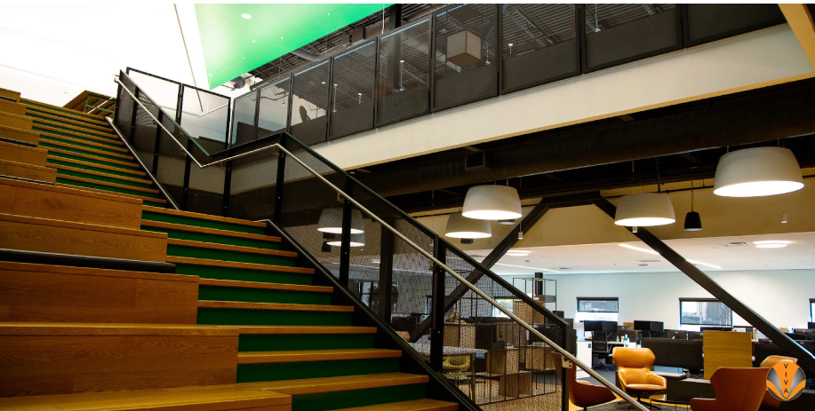 Modern office staircase with metal railings and wood steps.