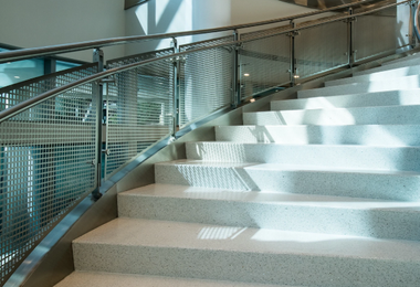 Staircase railing with perforated metal panel detail in modern interior design.