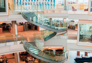 Modern office interior with curved glass staircase showcasing contemporary office railing design.