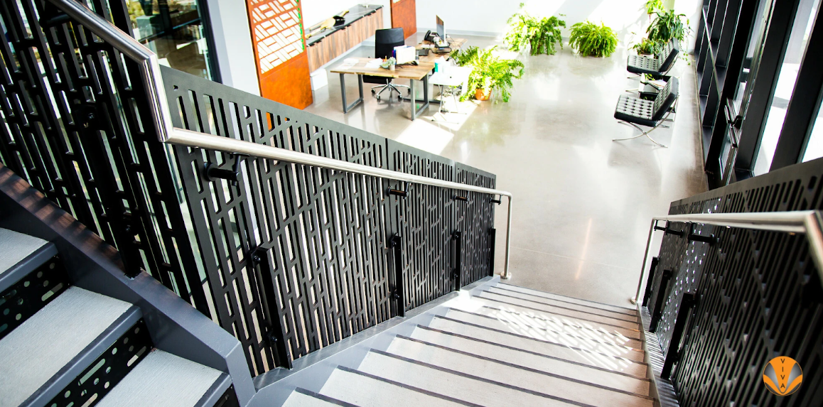 Modern staircase with perforated metal railing panels in a contemporary office interior.