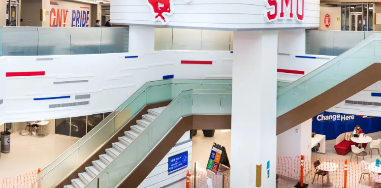 Modern interior staircase with glass railings in a university building.