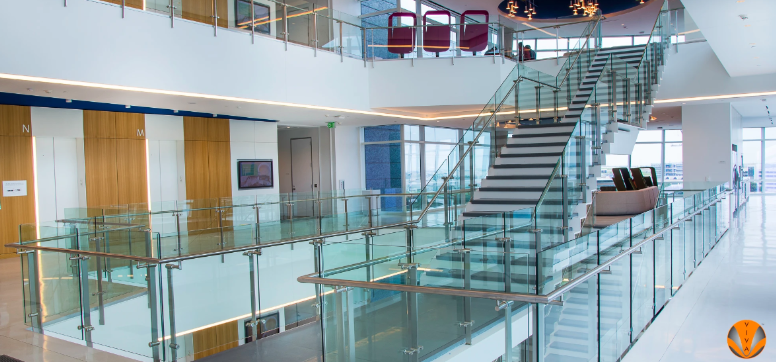 Modern office interior with glass railings and a central staircase in a multi-level atrium.