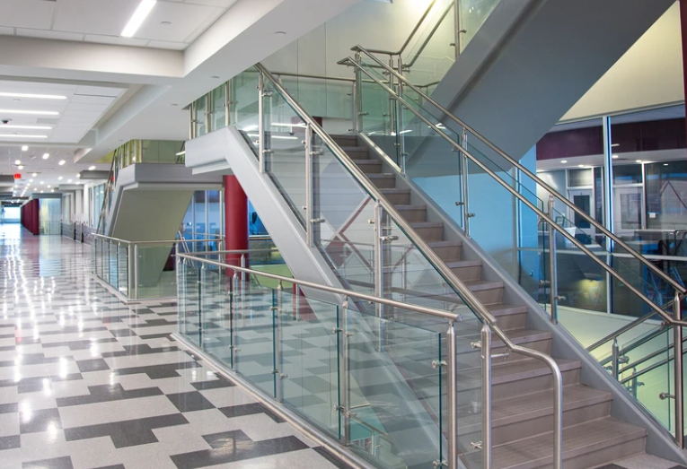 Modern steel and glass railing design for stairs and balcony in a school interior.