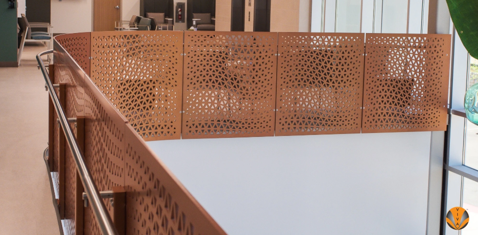 Interior walkway with decorative perforated metal railing panels and handrail.