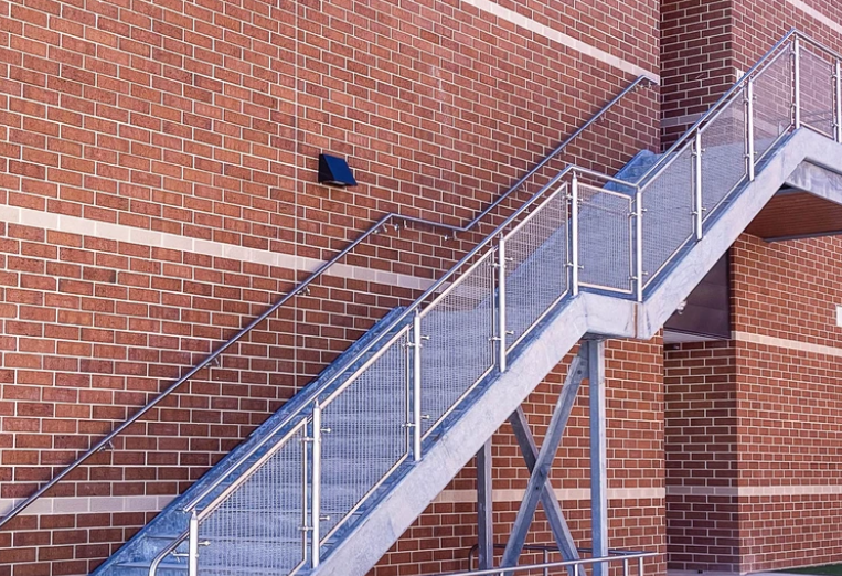 An image of concrete stairs with a mesh cable railing infill.