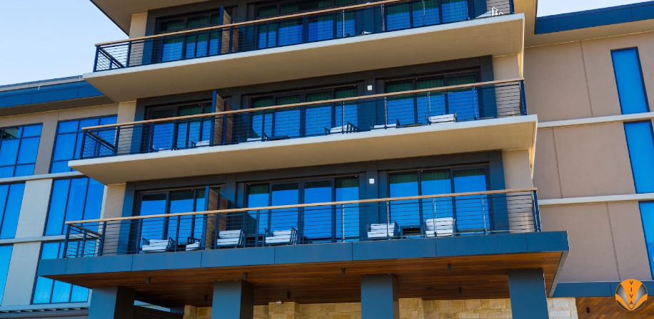 Contemporary building exterior featuring black metal balcony handrails and large glass windows.