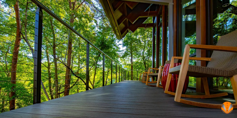 Cable railing on a wooden deck surrounded by trees.