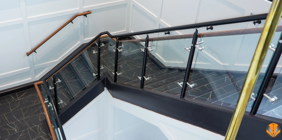 Modern staircase with glass and metal railings featuring wood accents.