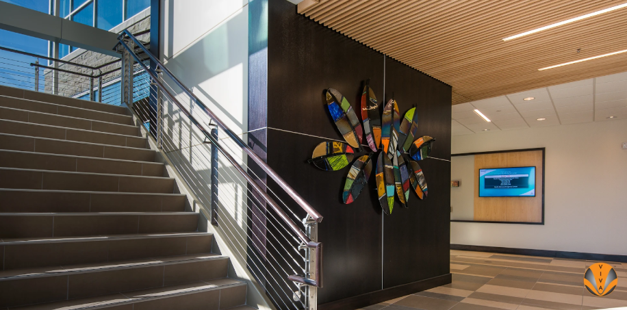 Modern interior staircase with stainless steel cable railings beside colorful wall art.
