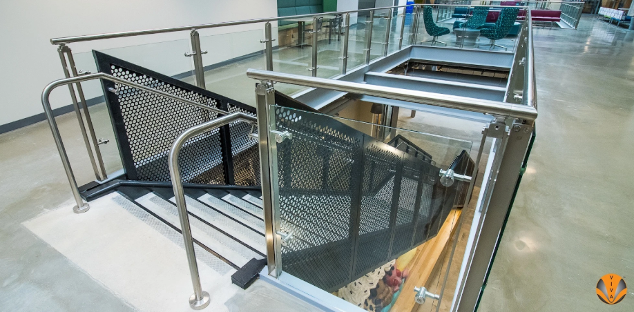 Modern indoor staircase with stainless steel and glass railings designed to meet code compliance standards.