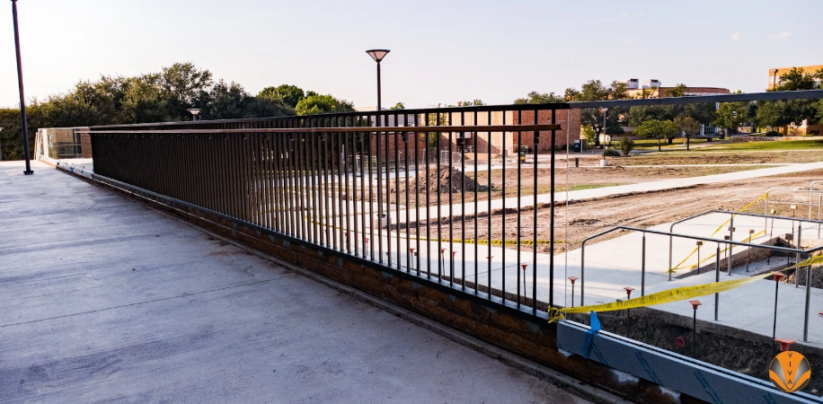 Black metal railing installed on a concrete overlook at a construction site.