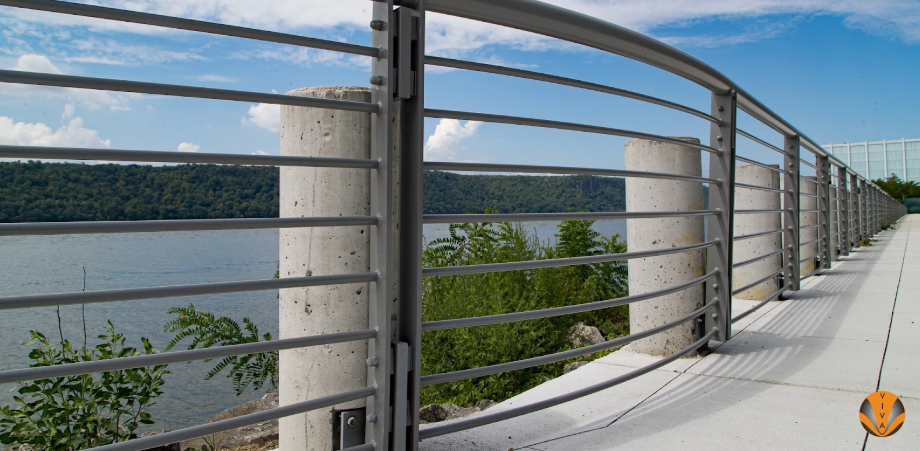 Horizontal metal railing on a riverside walkway labeled Extell Yonkers.