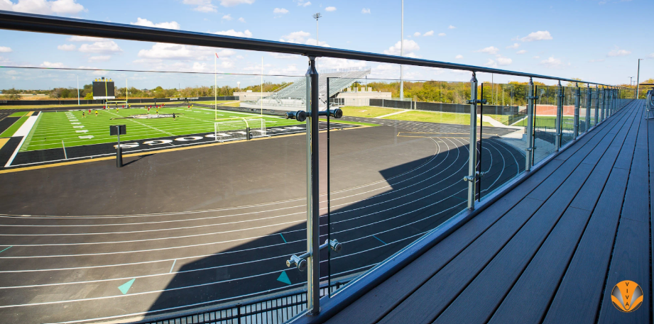 Glass railing at Royse City ISD Events Center overlooking a track and field stadium.