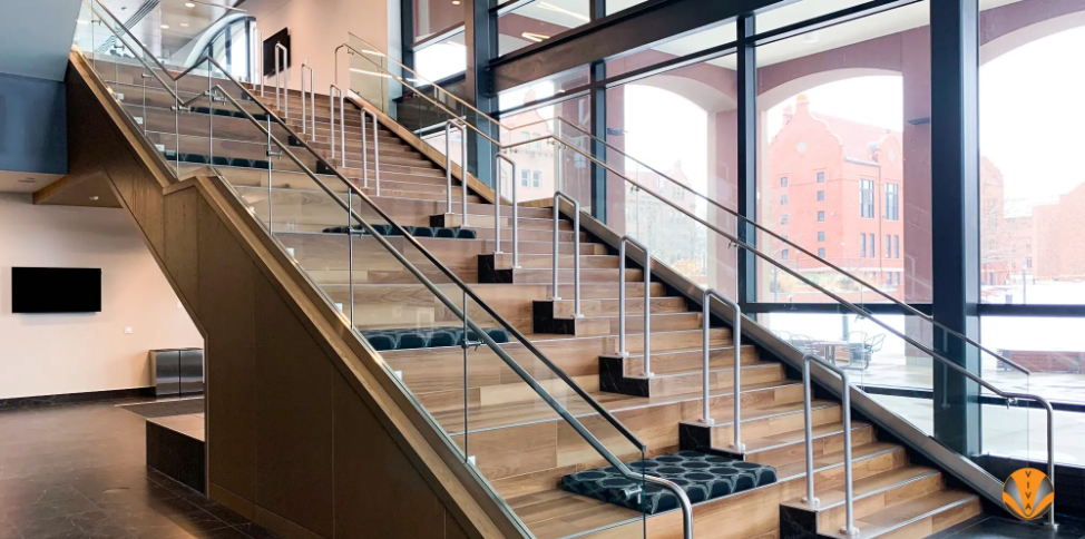 Modern interior staircase with wood steps, glass railings, and metal handrails.