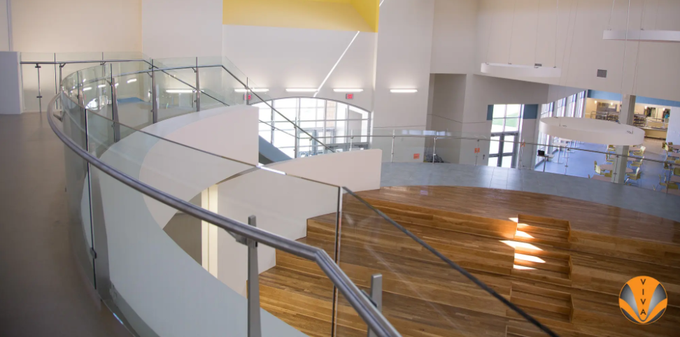 Modern interior with curved glass railings and tiered wooden seating.