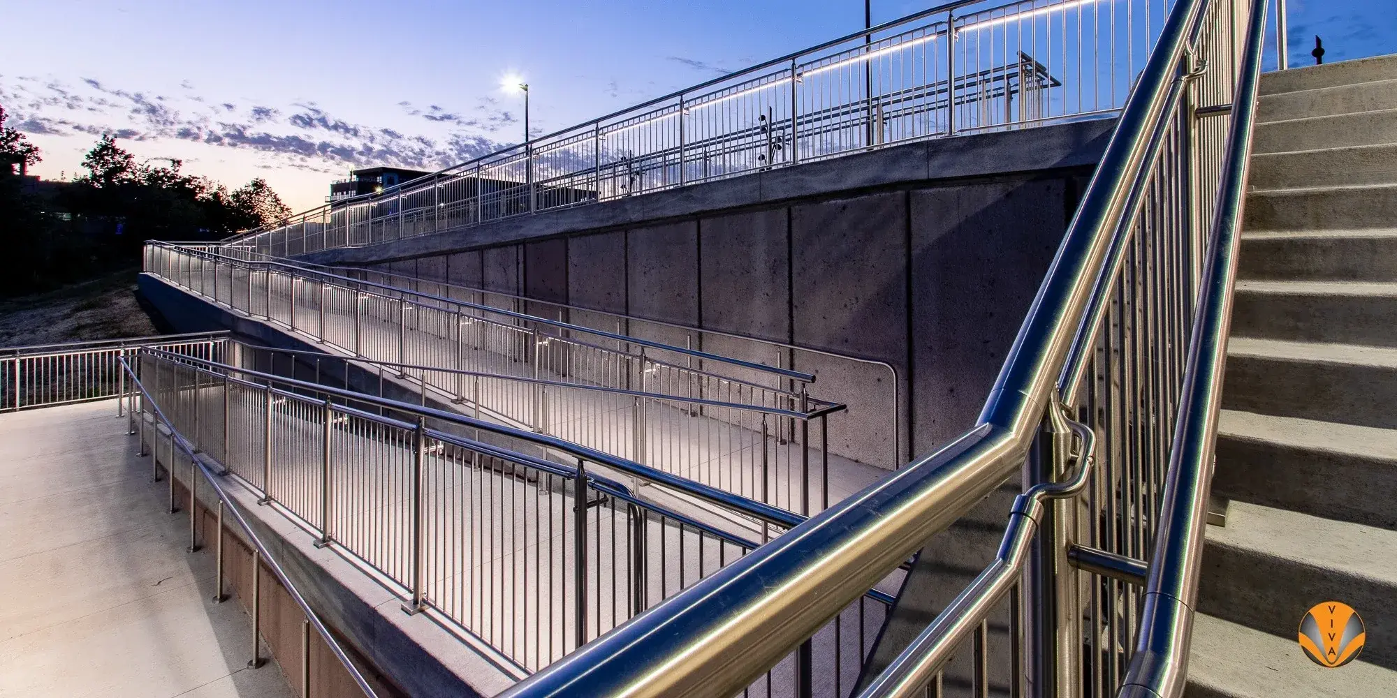 Metal picket railing system with integrated linear lighting at an outdoor amphitheatre.