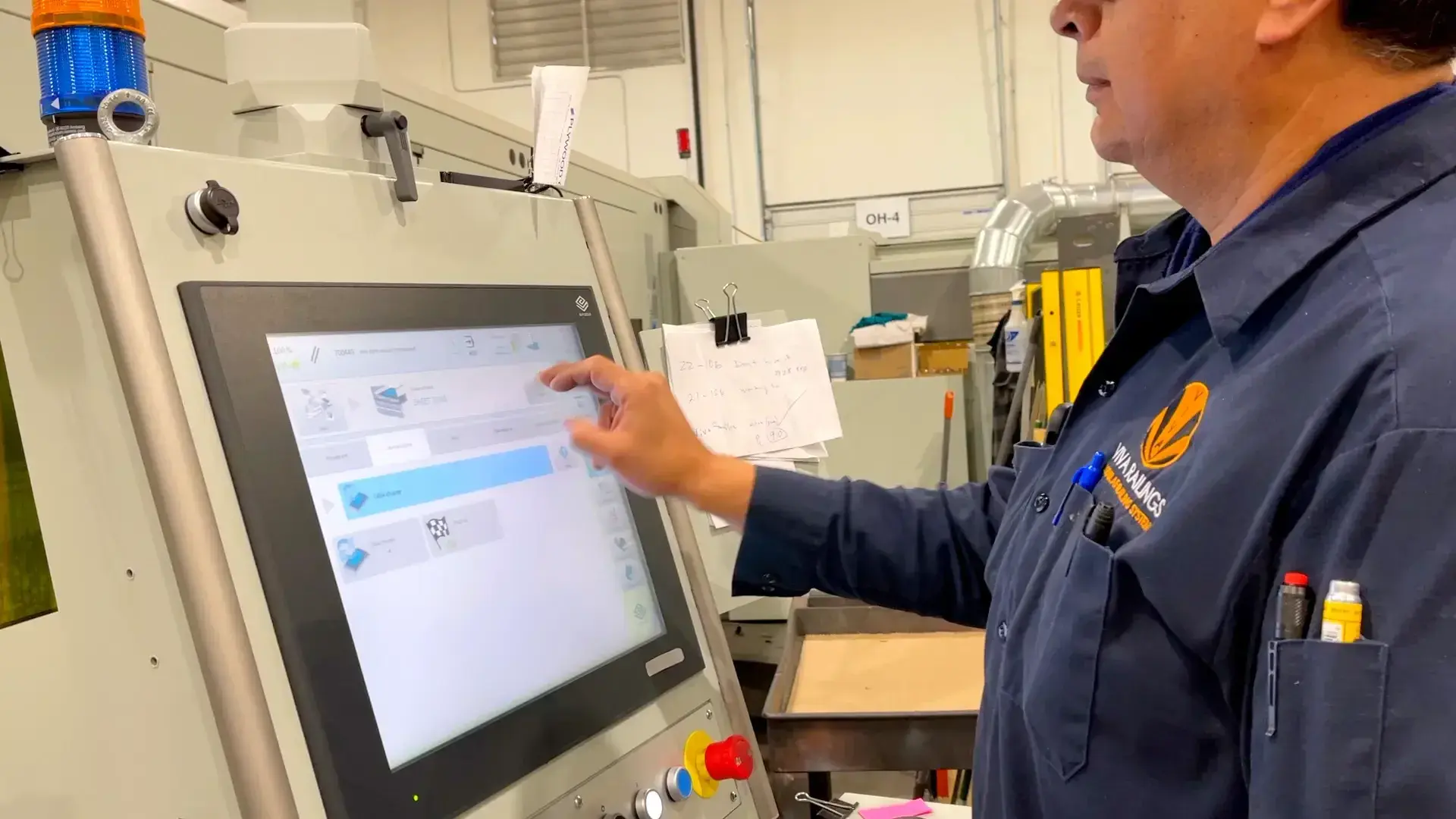 Manufacturing technician operating a touchscreen control panel on industrial equipment.